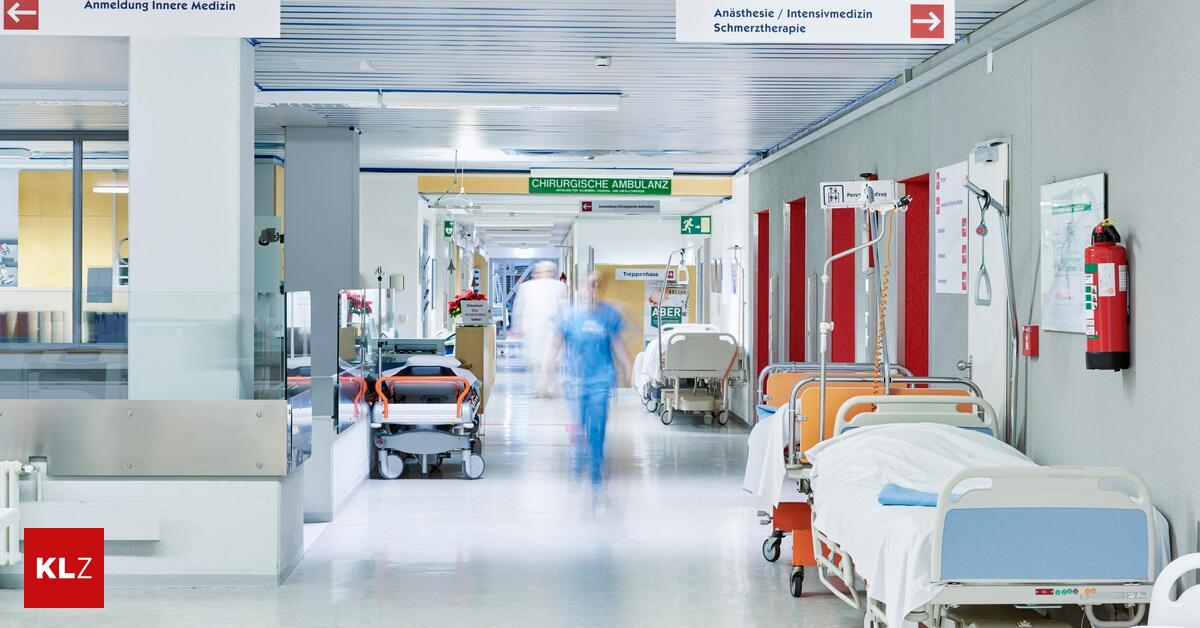 Flur im Krankenhaus mit unscharfem Arzt in Bewegung und Lift rot und Bett