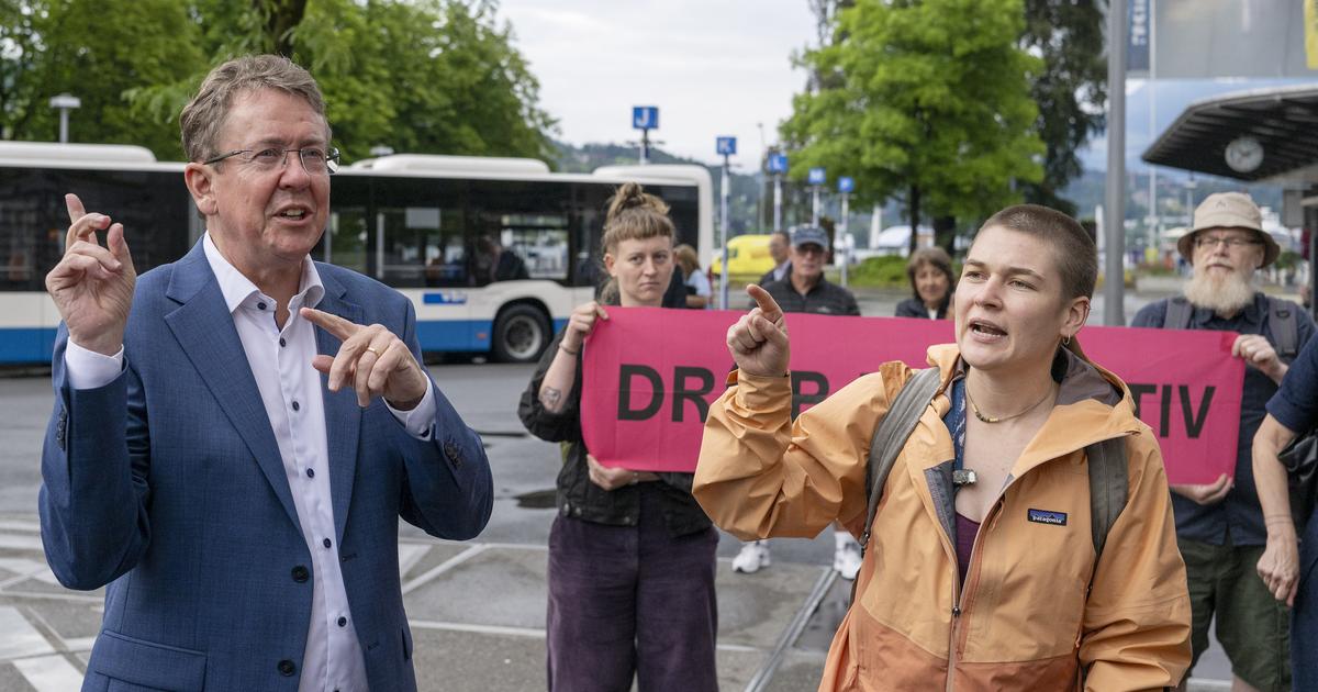 Albert Rösti aux côtés d'une militante pro-climat à Lucerne lors de la visite annuelle du ministre, le 1er juillet 2026. [KEYSTONE - PETER SCHNEIDER]