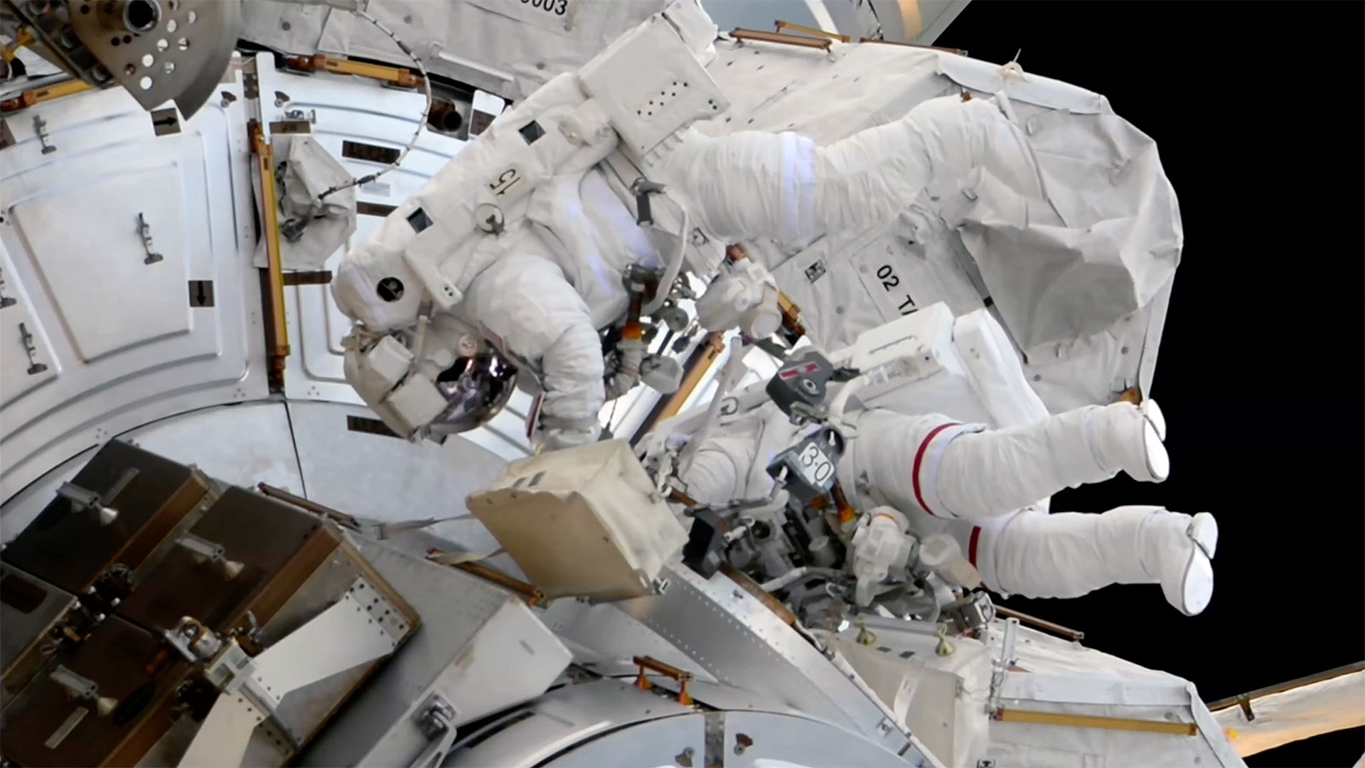 Two astronauts complete camera and docking aid replacements on spacewalk outside space station