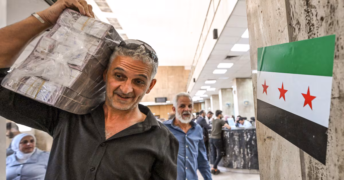 A man carrying Syrian pounds leaves the central bank in Damascus, in May 2025. Inflation is expected to rise. AFP